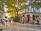 Belebter Hein-Köllisch-Platz in Hamburg mit Straßencafé, Passant:innen und sommerlicher Abendstimmung