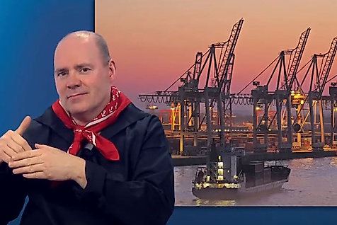 Mann gebärdet vor Panorama des Hamburger Hafens bei Sonnenuntergang – barrierefreie Infos zum Hafenleben.