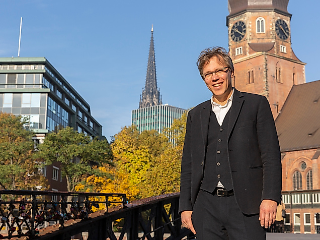 Pastor Frank Engelbrecht auf Brücke in Hamburg mit Blick auf Hauptkirche St. Katharinen und moderne Architektur