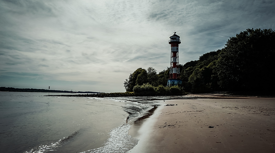 Leuchtturm Wittenbergen am Elbstrand mit nassem Sand, flachen Wellen und bewölktem Himmel