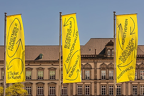 Gelbe Kunstmeile-Fahnen vor klassizistischer Fassade am Hamburger Glockengießerwall bei blauem Himmel
