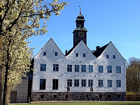 Weißes Herrenhaus unter blauem Himmel im Sonnenschein.