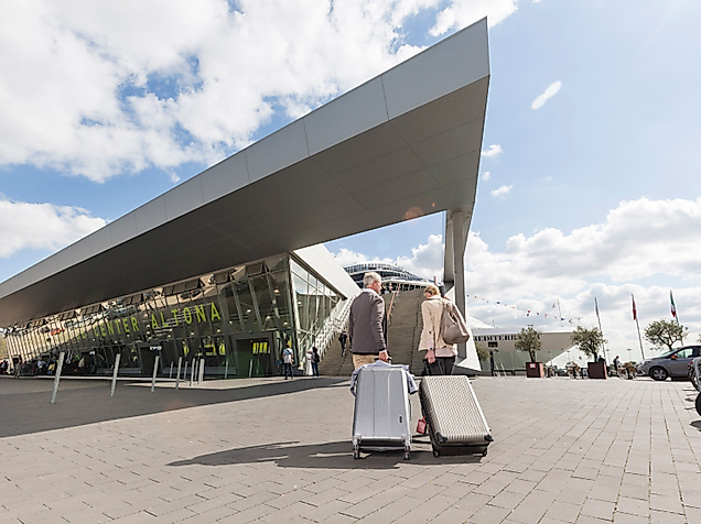 Reisender mit Rollkoffern vor dem modernen Terminalgebäude des Cruise Center Altona in Hamburg