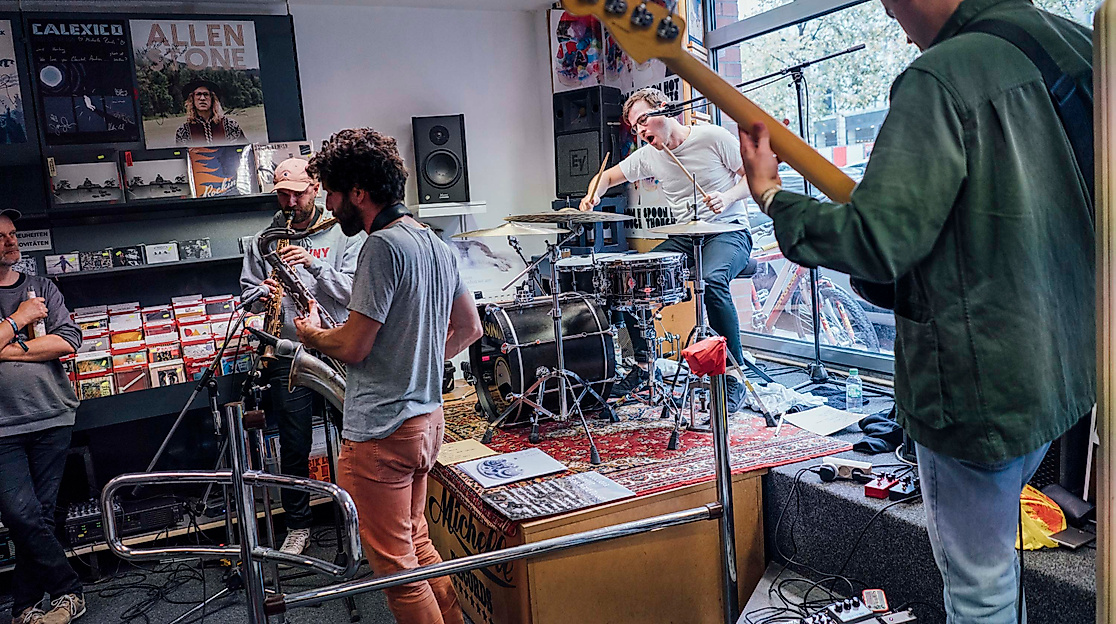 Live-Session einer Band in kleinem Plattenladen beim Reeperbahn Festival, intime Konzertatmosphäre.