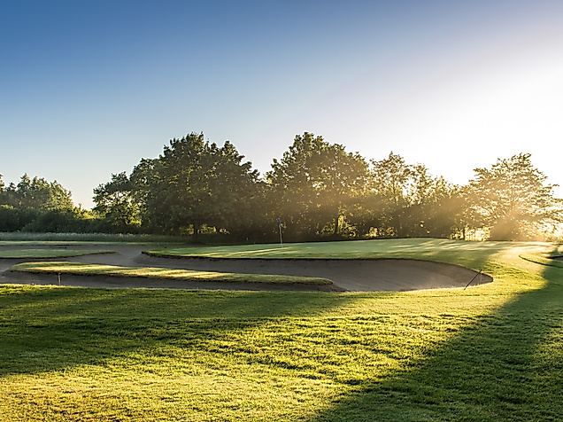 Sonnenbeschienener Fairway im Golf Club Jersbek bei Hamburg mit Bunker und umrahmenden Bäumen