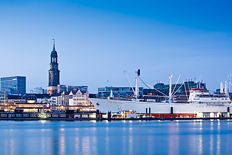 Cap San Diego im Hamburger Hafen bei Abendlicht mit Blick auf den Michel und die Stadt