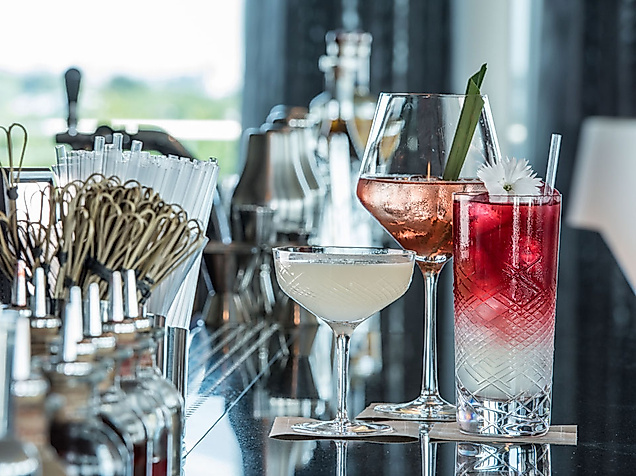 Drei stilvoll angerichtete Cocktails auf glänzender Theke in moderner Hamburger Cocktailbar