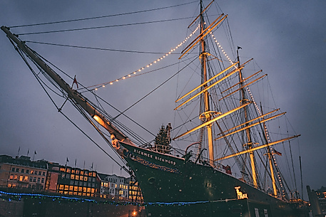 Historic sailing ship festively lit with Christmas lights at dusk in Hamburg’s harbor