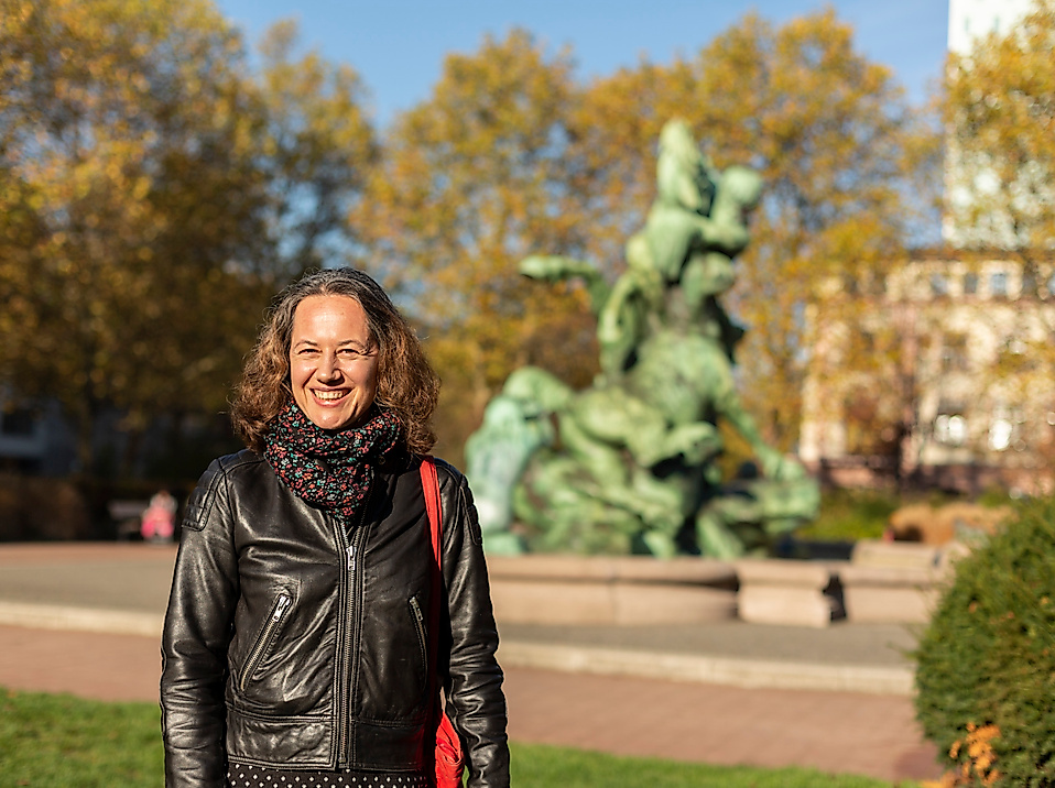 Frau im herbstlichen Park in Hamburg Altona-Ottensen vor bronzener Brunnenplastik
