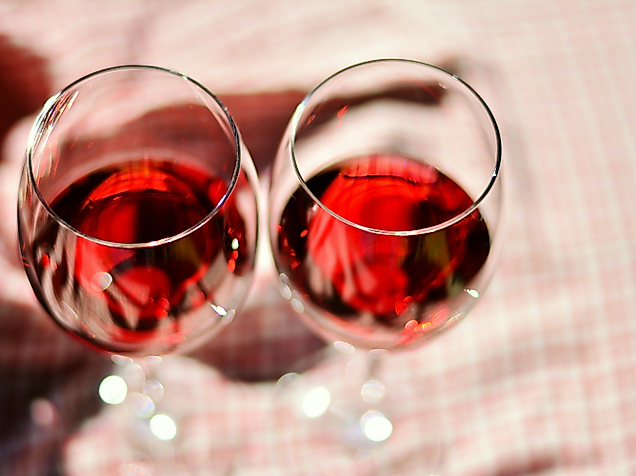 Zwei gefüllte Rotweingläser auf karierter Tischdecke bei stimmungsvoller Weinverkostung in Hamburg