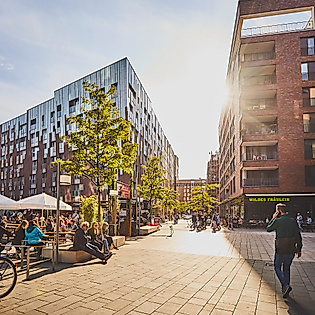 Überseeboulevard in der HafenCity Hamburg mit Cafés, Menschen und moderner Architektur bei Sonnenschein