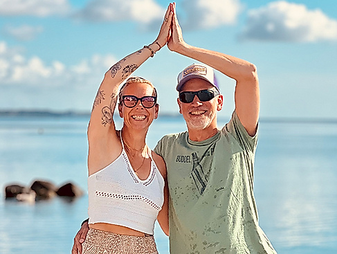 Frau und Mann bei Yoga am Strand von Scharbeutz und Haffkrug an der Ostsee in einer Yogaübung vor dem Meer
