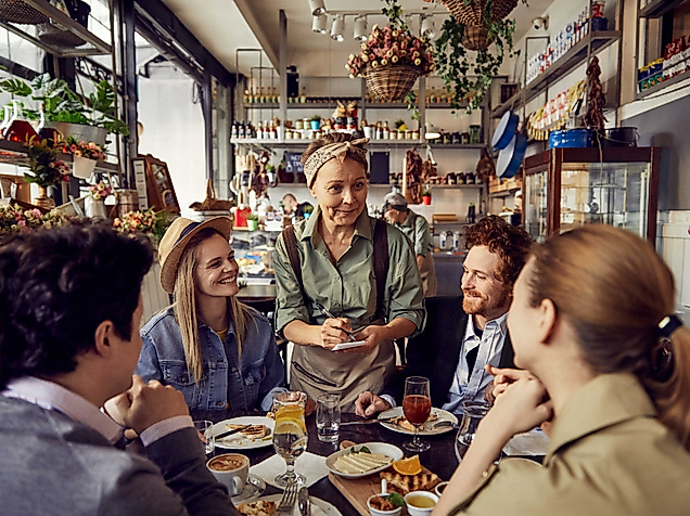 Bedienung, die von 4 Menschen in einem Restaurant die Bestellung aufnimmt. 