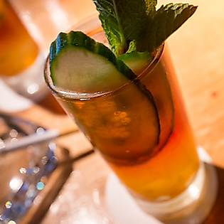 Cocktail mit Gurke und Minze in der Boilerman Bar, stimmungsvoll beleuchtet auf Holztresen