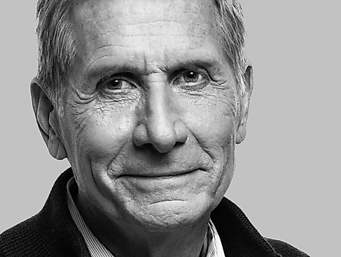 Black-and-white portrait photo of an older male-identified person with short hair and a dark collar.