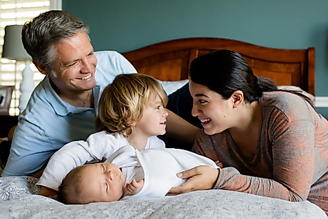 Mann, Frau und zwei Kinder zusammen auf einem Bett
