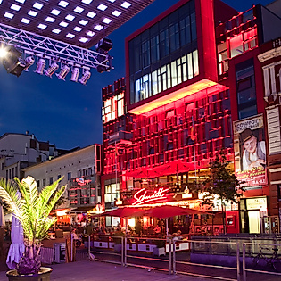 Beleuchtetes Schmidt Theater auf der Reeperbahn bei Nacht, umgeben von Bars und Lichtinstallationen