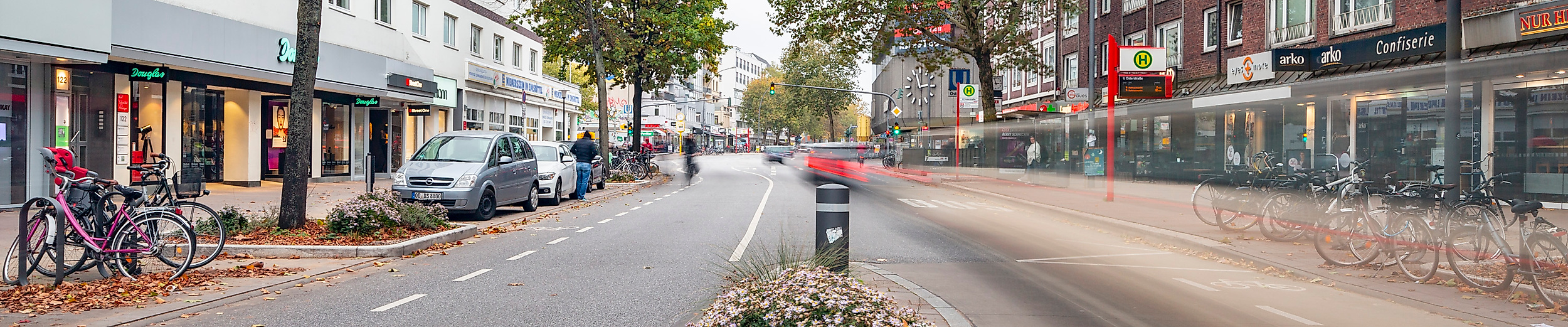 Osterstraße in Hamburg-Eimsbüttel mit Radweg, Herbstbäumen und Geschäften auf beiden Seiten