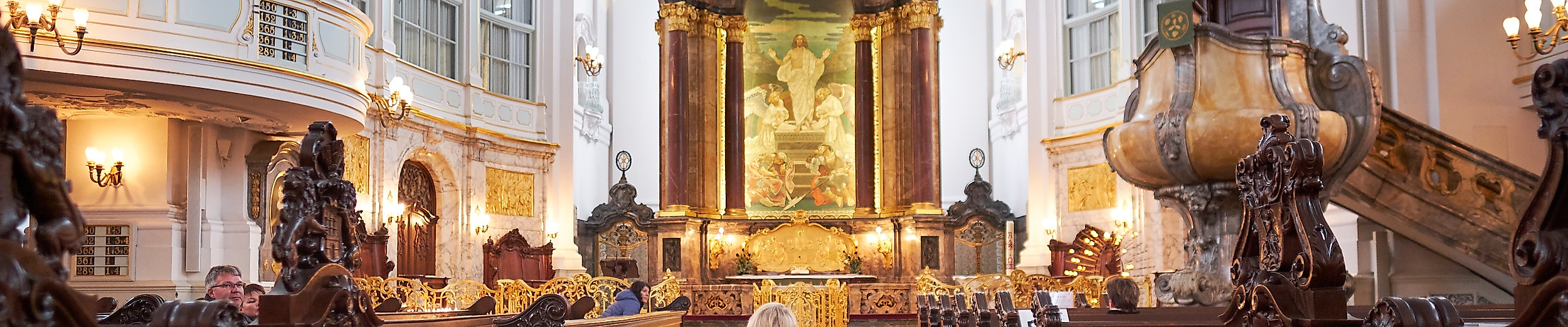 Rollstuhlnutzerin mit Assistenzhund im barrierefrei zugänglichen Kirchenschiff des Hamburger Michel.