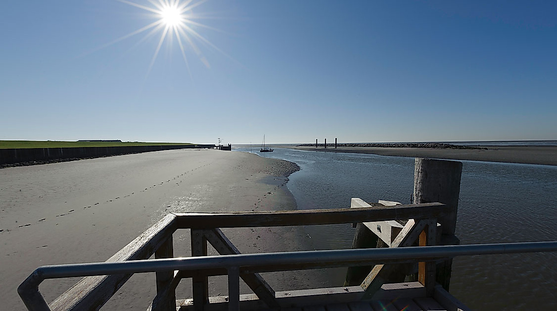 Wattlandschaft am Anleger Neuwerk bei Sonnenschein mit Holzgeländer und Blick Richtung Nordsee