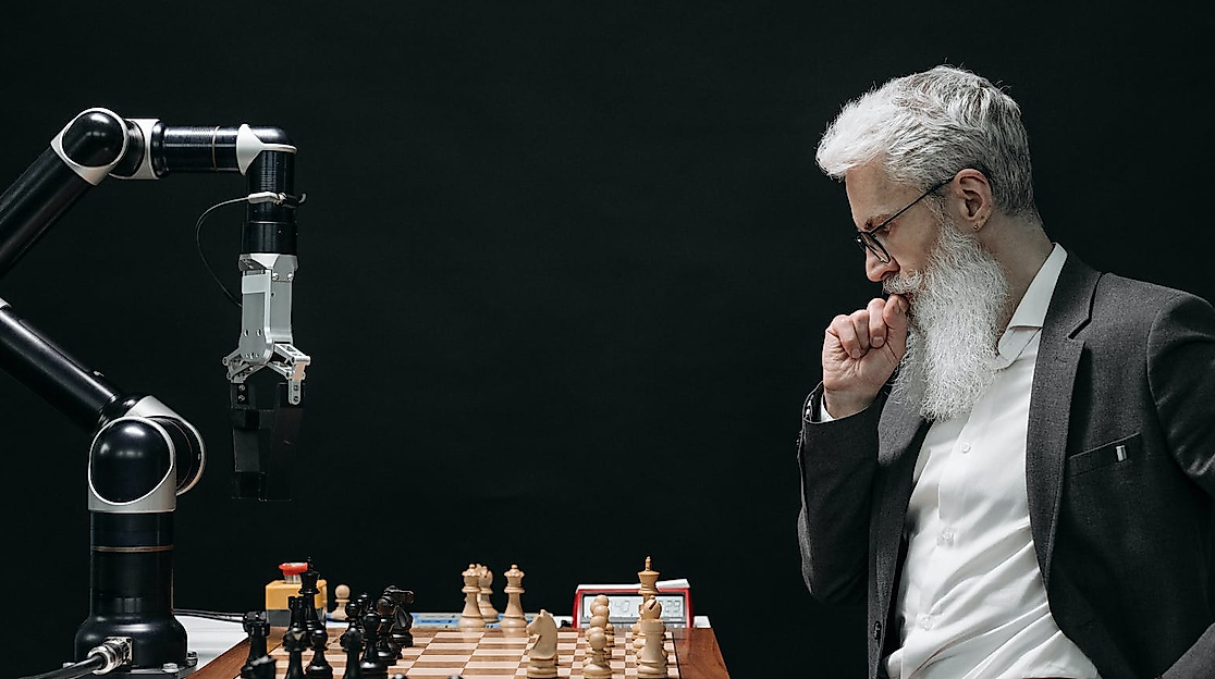 Ein Mann mit weißem Bart spielt Schach gegen einen Computer.