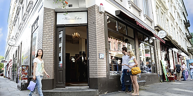 Menschen flanieren entlang kleiner Läden an einer Straßenecke im alternativen Hamburger Karoviertel