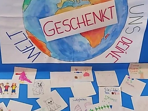 Bild mit Welt und Text `Du hast und Deine Welt geschenkt` und kleinen Bildern von Kindern gemalt