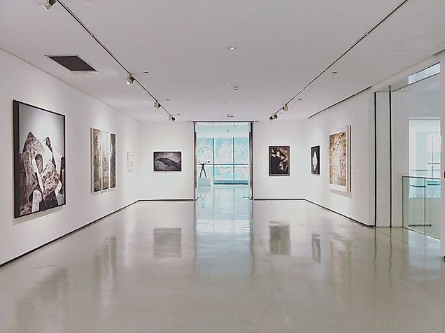 Heller Galerieraum mit modernen Gemälden an weißen Wänden und glänzendem Boden