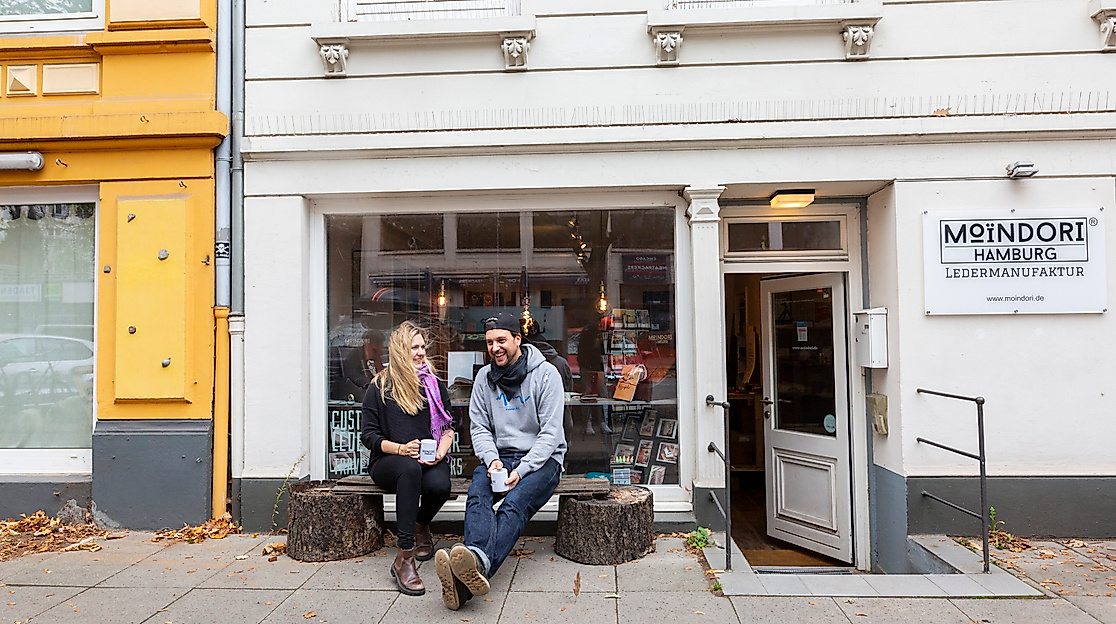 Atelier MoinDori in Hamburg mit zwei Personen auf der Bank vor dem Eingang und kreativem Schaufenster