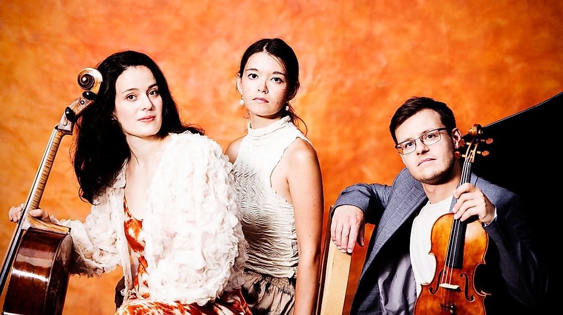 Musikertrio vor orangefarbenem Hintergrund