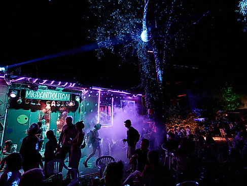 Migrantpolitan bei Nacht in Partystimmung mit Nebel und buntem Licht