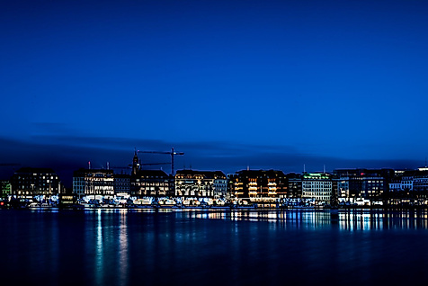 Beleuchtete Binnenalster mit Jungfernstieg und Spiegelungen im Wasser unter klarem Nachthimmel