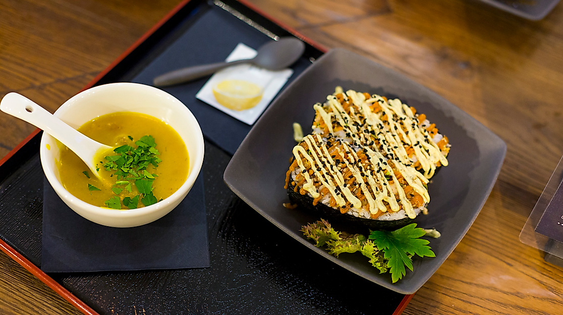 Asiatisches Gericht mit Misosuppe und herzhaft belegtem Okonomiyaki auf Tablett, serviert in modernem Ambiente