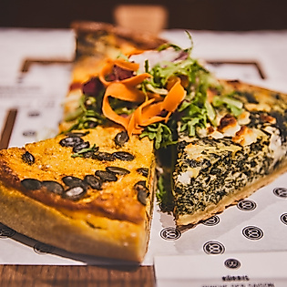 Zwei Stücke herzhafte Quiche mit Gemüse und frischem Salat, serviert im Restaurant Cöllns Mutterland