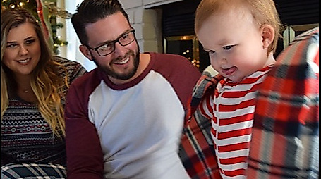 Eltern mit Kleinkind in weihnachtlich geschmückter Wohnung