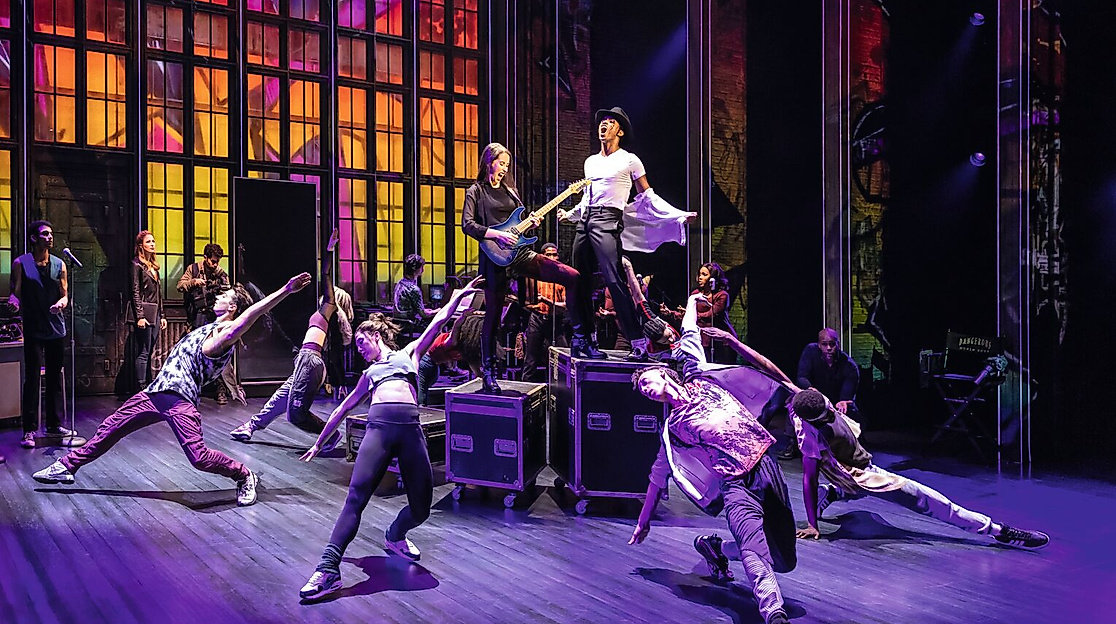 Szenenbild Michael Jackson: Michael Jackson auf einer Bühne von Tänzer:innen umgeben. 