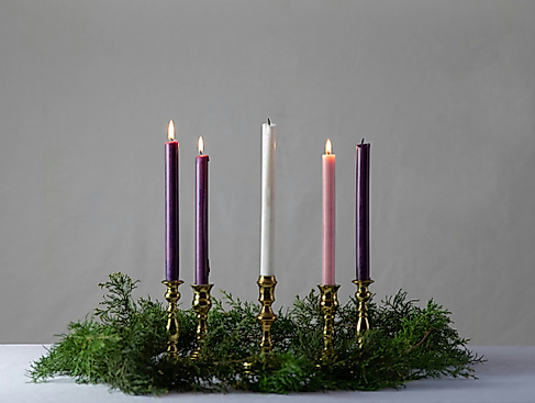 drei Kerzen brennen in einem Gesteck