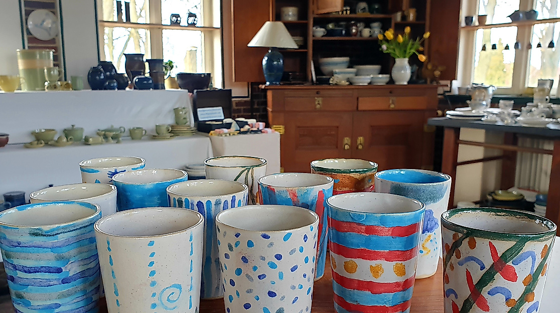 Fantasievoll bemalte Becher, die am Tag der offenen Töpferei 2025 in unserer Werkstatt entstanden sind.