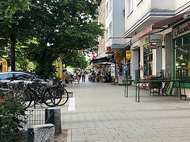 Straßenszene an der Weidenallee in Hamburg mit Cafés, kleinen Läden und abgestellten Fahrrädern im Schatten