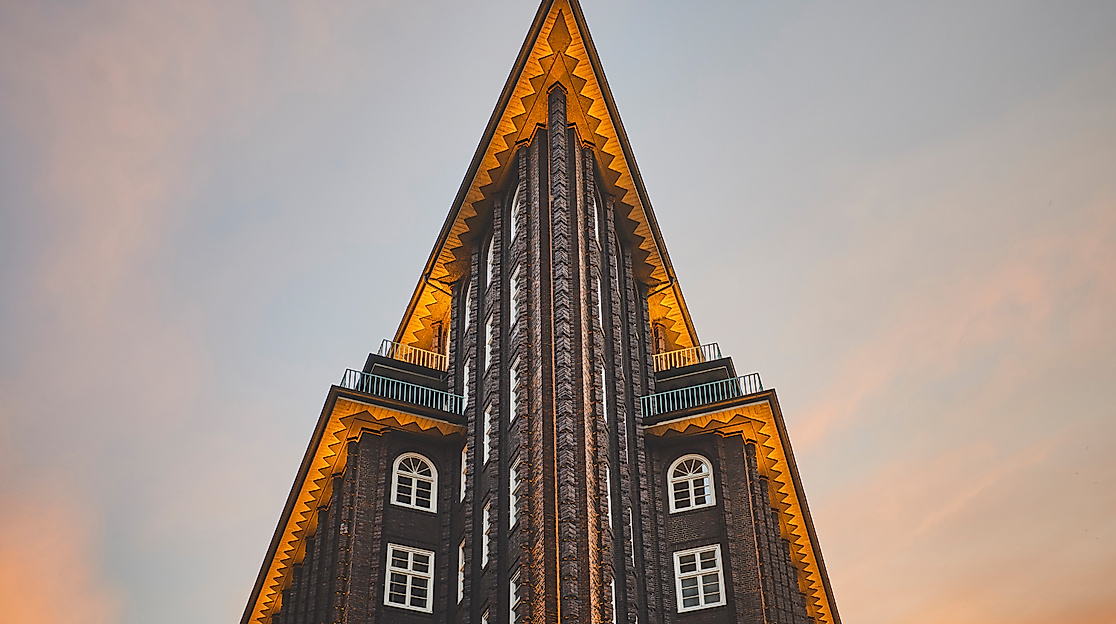 Beleuchtete Gebäudespitze des Chilehauses in Hamburg vor farbigem Abendhimmel