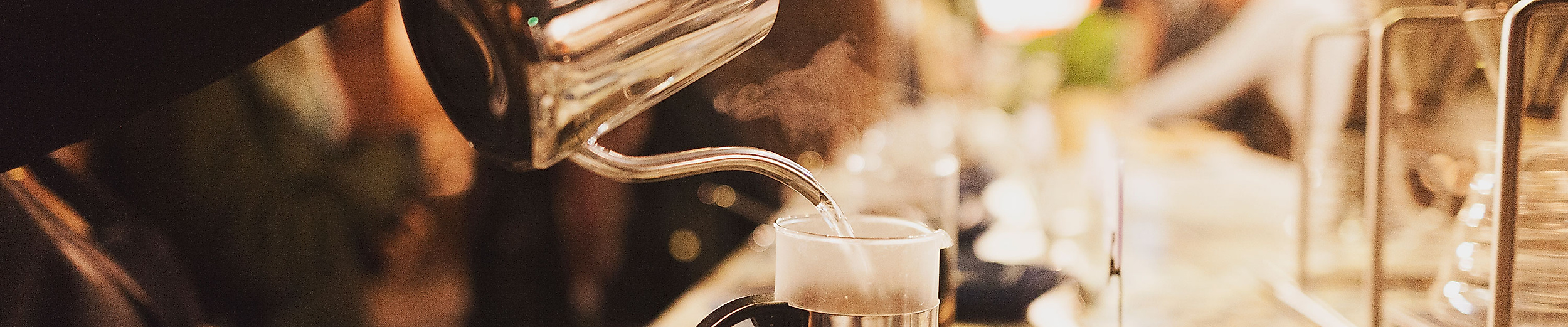 Barista gießt frischen Kaffee in Tassen an beleuchteter Theke mit gemütlicher Atmosphäre