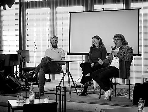 Drei Personen sitzen auf einem Panel und unterhalten sich.
