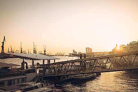 Sonnenuntergang an den Landungsbrücken mit Blick auf Elbe, Schiffe und historische Gebäude im Gegenlicht