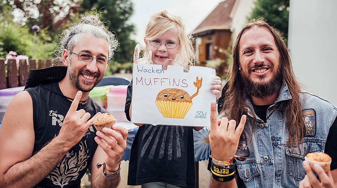 Zwei Metal-Fans mit Kind halten selbstgemaltes Wacken-Bild