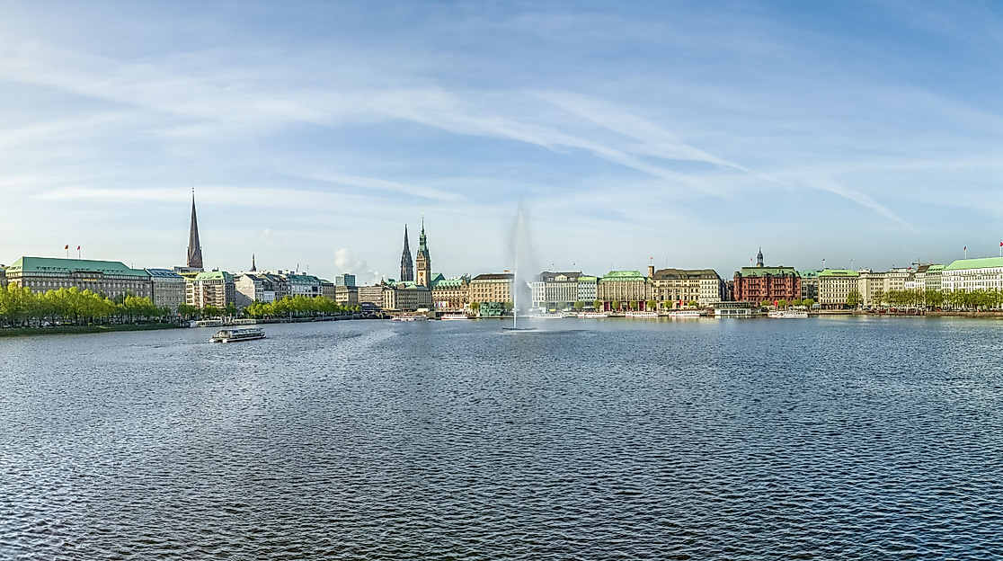 Panoramablick auf die Binnenalster mit glitzerndem Wasser, grünen Ufern und Hamburger Stadtsilhouette