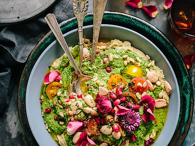 Farbenfrohe vegetarische Bowl mit Gemüse, Kräutern und essbaren Blüten, stilvoll angerichtet mit Besteck