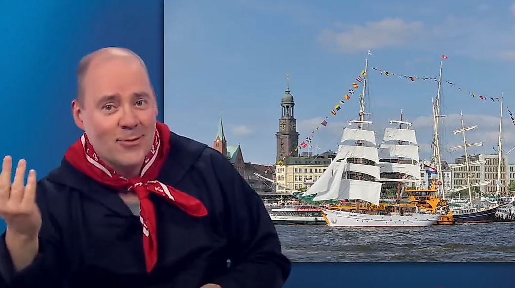 Mann begrüßt in Gebärdensprache vor Hamburg-Motiv mit Segelschiff und Michel – barrierefreier Einstieg für Gehörlose.