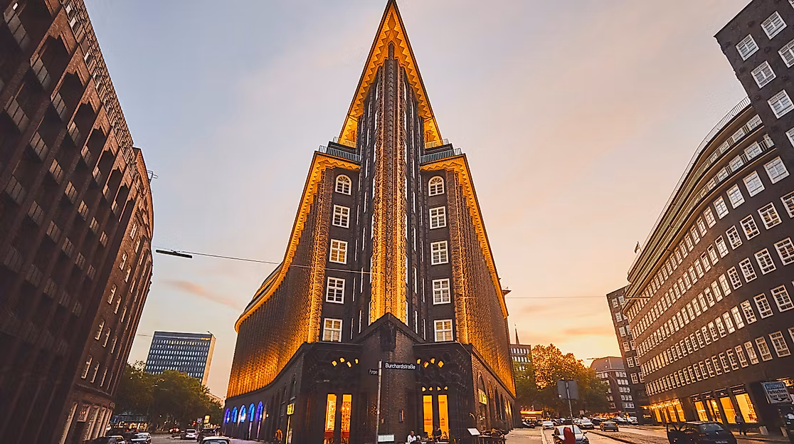 Spitz zulaufende Front des beleuchteten Chilehauses in Hamburg bei Sonnenuntergang