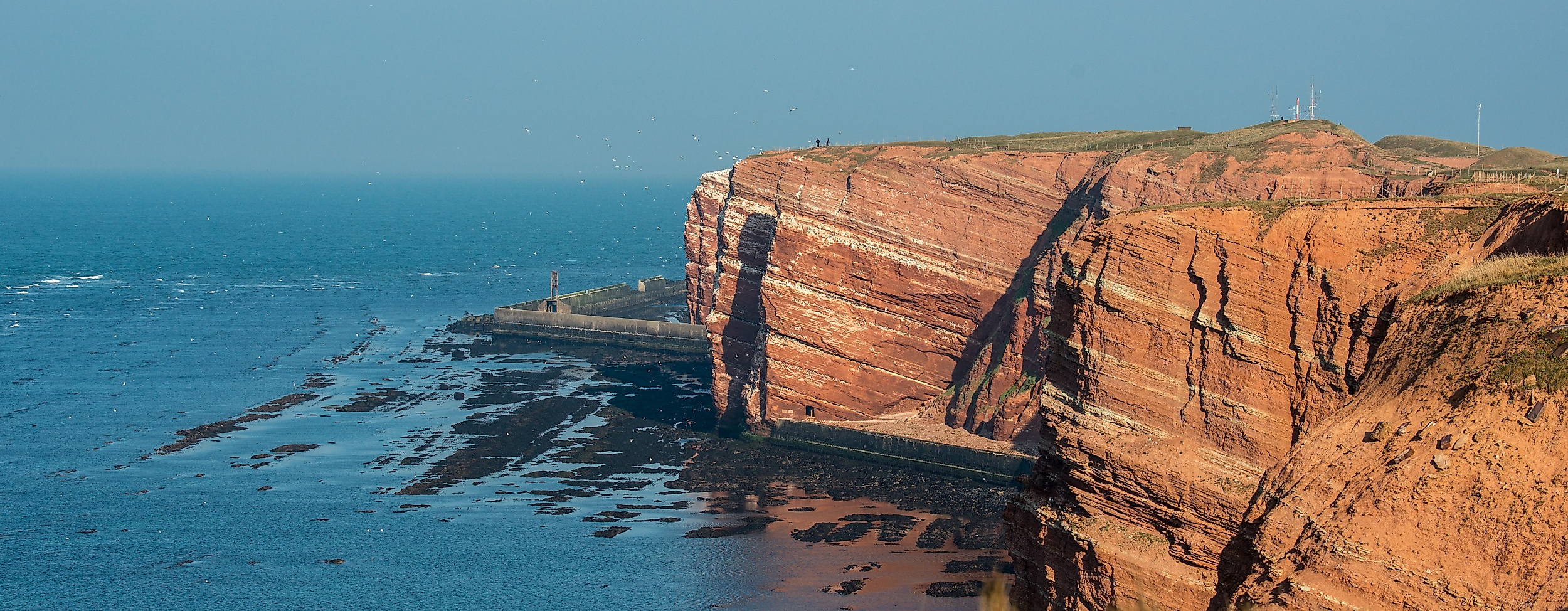 Rote Steilküste von Helgoland mit Blick auf die Nordsee bei klarer Sicht und Sonnenschein