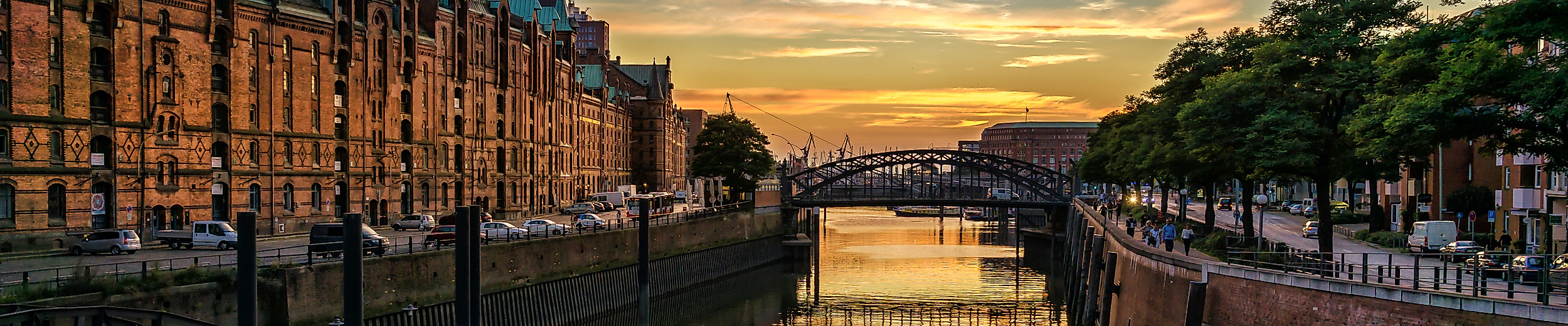 Abendstimmung in der Speicherstadt mit beleuchteten Fassaden und Spiegelung im Wasser des Fleets